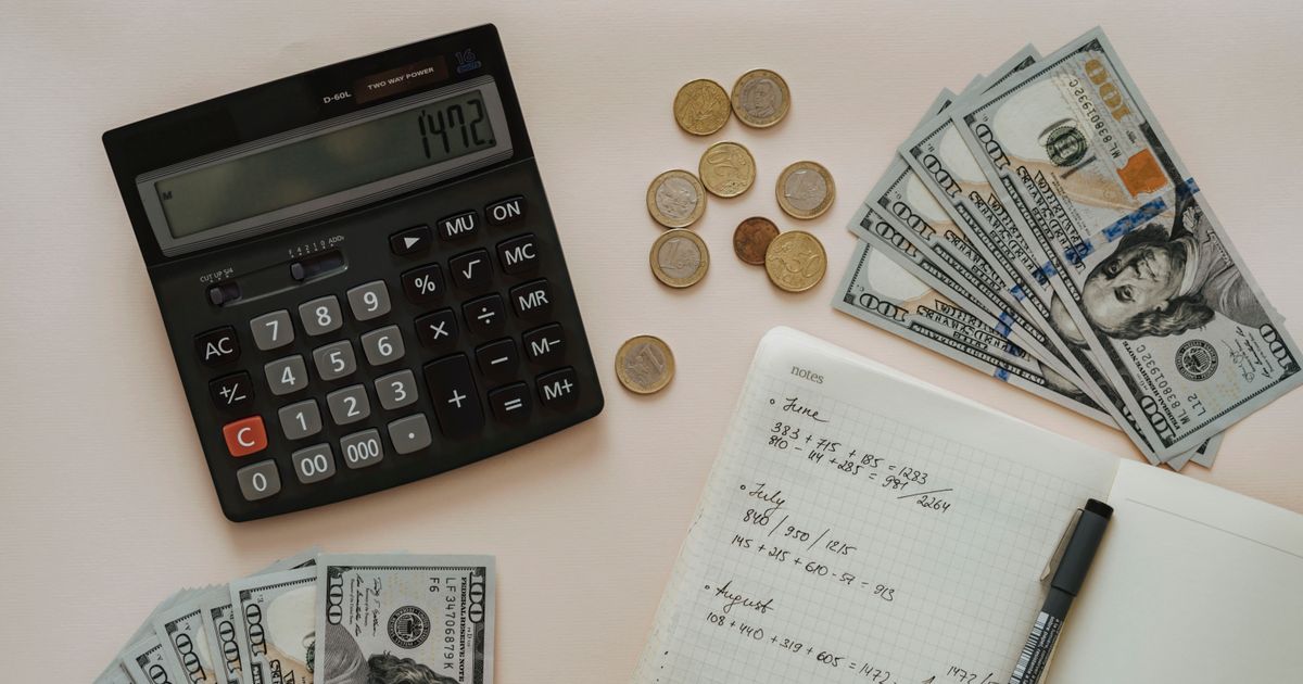 Calculator, coins and handwritten budget notes on a desk