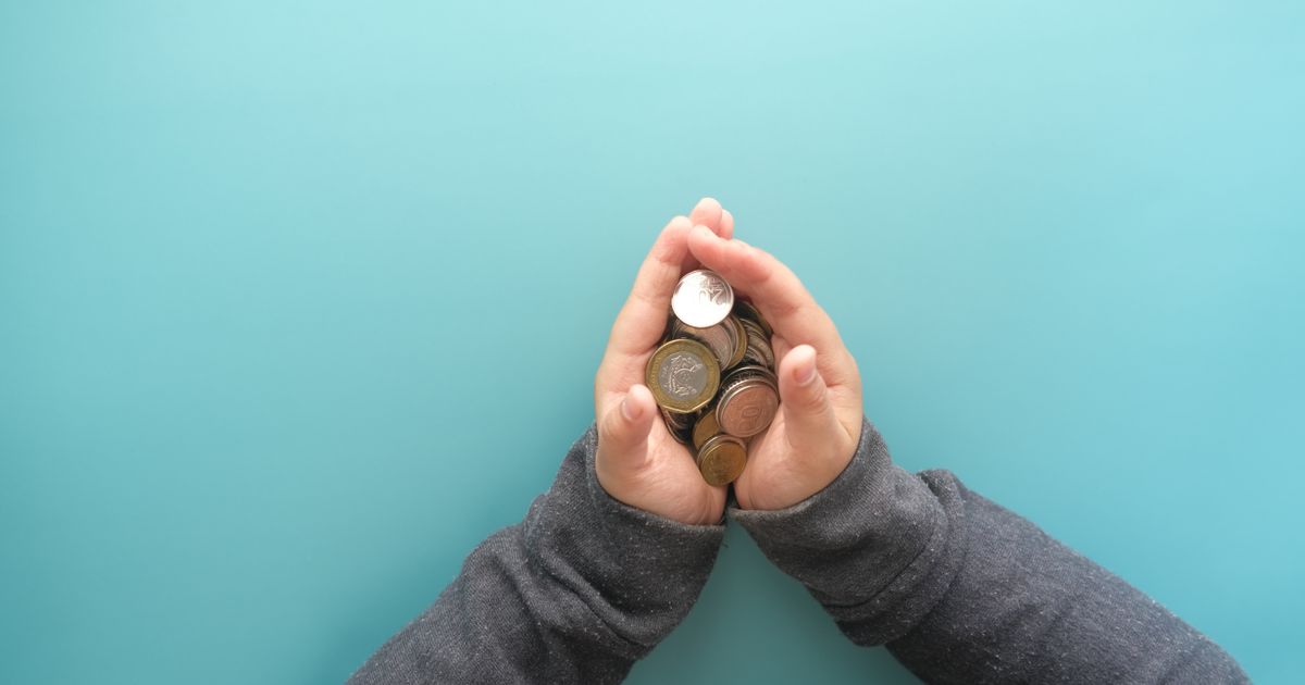 Hands holding coins against a blue background