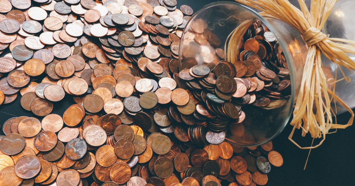 A jar of US pennies spilled across a dark surface