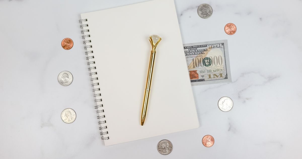 Notebook, coins and a US dollar bill on a light desk